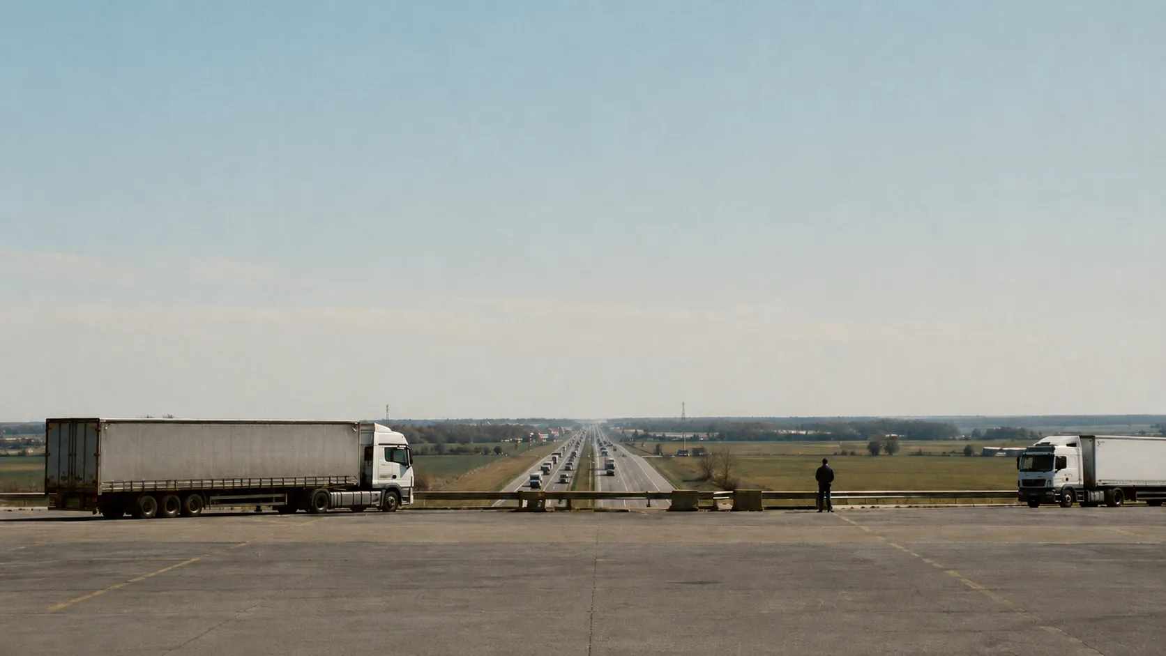 Caminhões diante de uma rodovia movimentada